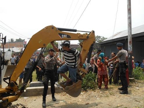 Pelaksanaan eksekusi yang berakhir ricuh. Tampak salah satu tergugat menaiki alat berat      